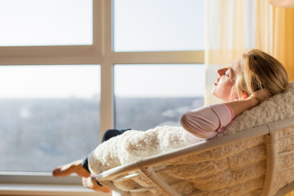A women relaxing in their chair looking out the window.